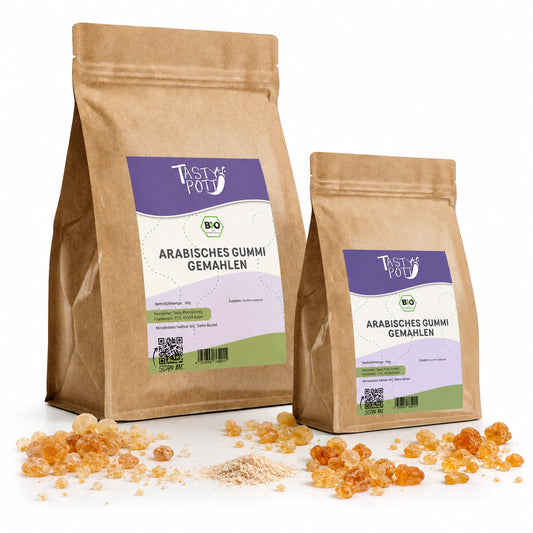 Zwei Tasty Pott Beutel mit arabischem Gummi arabicum gemahlen, umgeben von Harzstücken und Pulver, stehend auf weißem Hintergrund.
