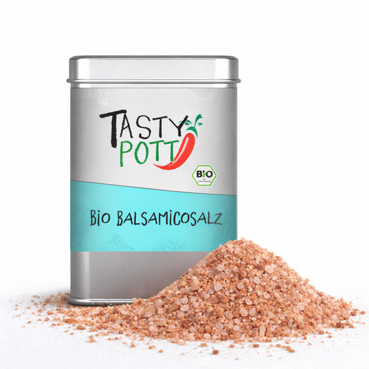 Silberne Dose Tasty Pott Bio Balsamicosalz mit türkisfarbenem Etikett, davor ein Haufen grobkörniges, rötliches Salz