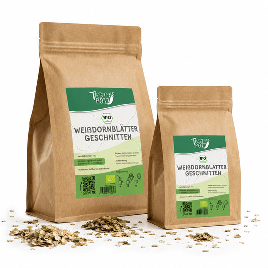 Zwei braune Beutel Tasty Pott Weißdornblätter mit Blüten geschnitten, 100g und 50g, stehend auf weißem Hintergrund, davor lose getrocknete Blätter.