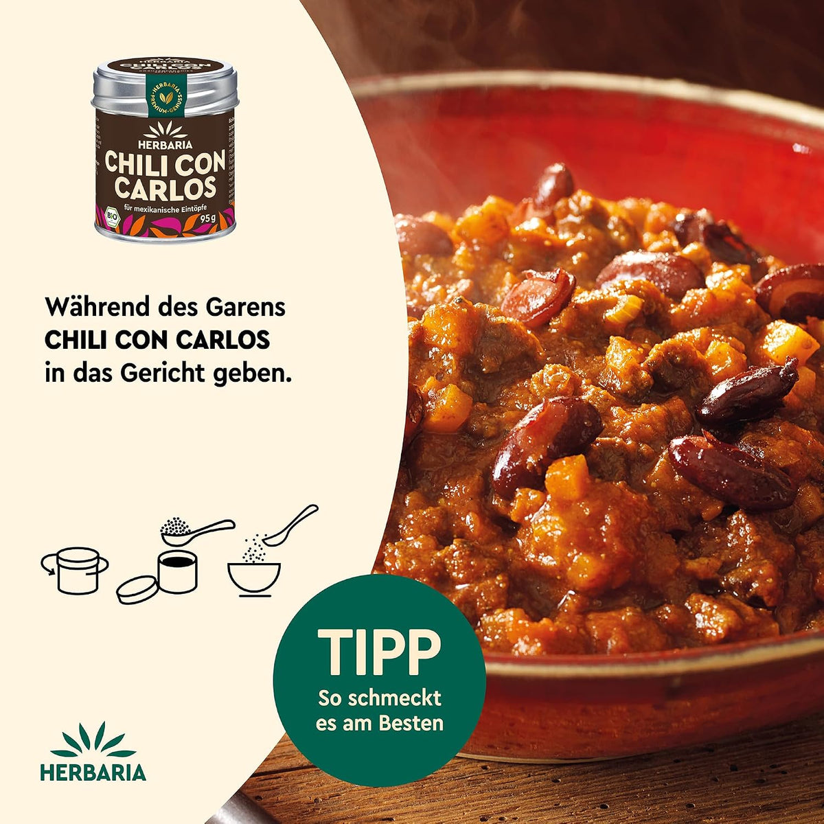 Nahaufnahme eines dampfenden Chili-Eintopfs in einem roten Topf, links daneben Herbaria Chili con Carlos Gewürzdose und Anwendungshinweis.