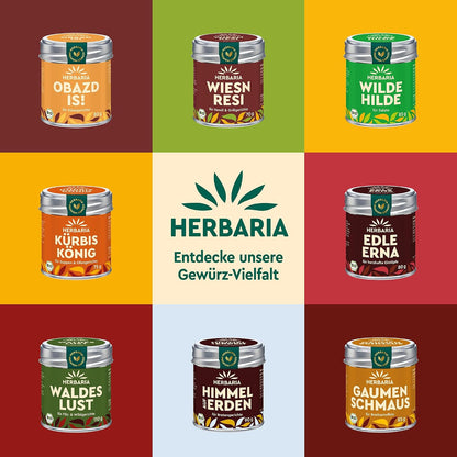 Neun verschiedene Herbaria Gewürzdosen, darunter Sissis Sünd, auf buntem Hintergrund, mittig das Herbaria Logo und der Hinweis auf Gewürz-Vielfalt.