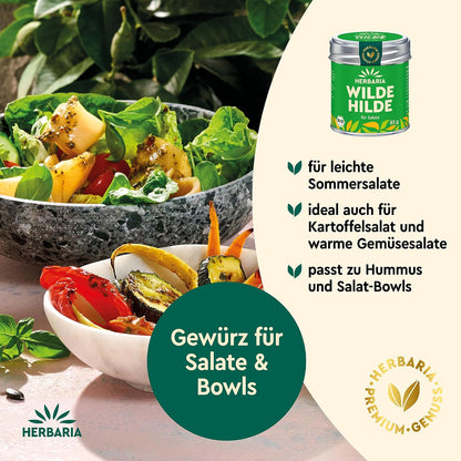 Salatschüssel mit frischem Blattsalat und Gemüse neben einer Schale mit gegrilltem Gemüse, daneben Herbaria Wilde Hilde Dose als Salatgewürz.