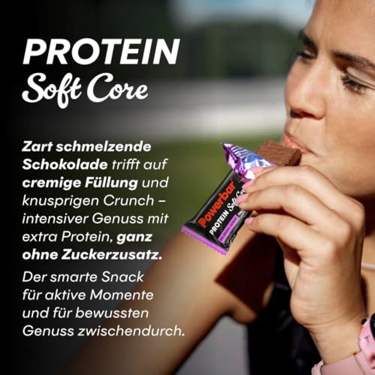Person beißt in einen Powerbar Soft Core Proteinriegel, der Riegel ist in der Hand sichtbar.